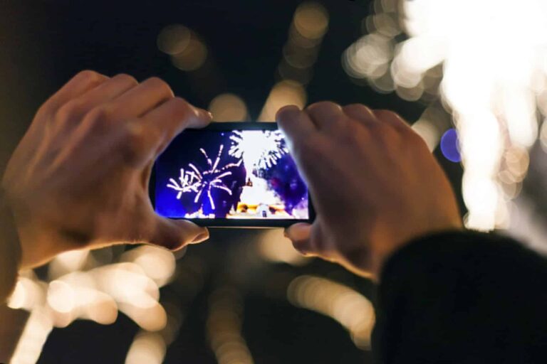 Human Hand Holding phone camera over fireworks