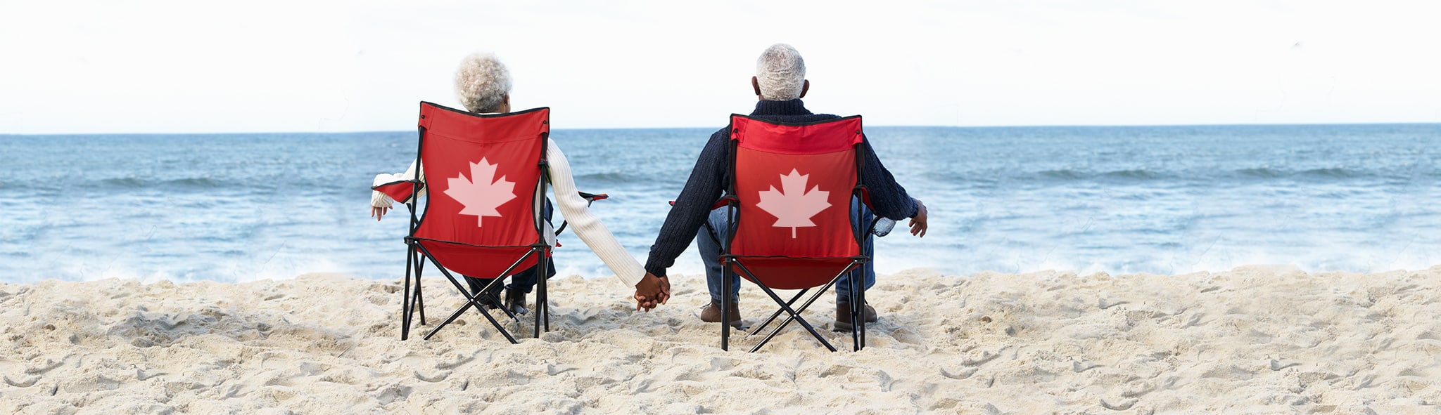 Senior Couple Sitting On Beach In Deck chairs